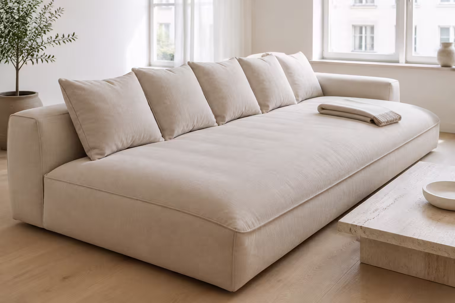 Djup ljus loungesoffa med låg rygg och stora lösa kuddar i ett ljust vardagsrum