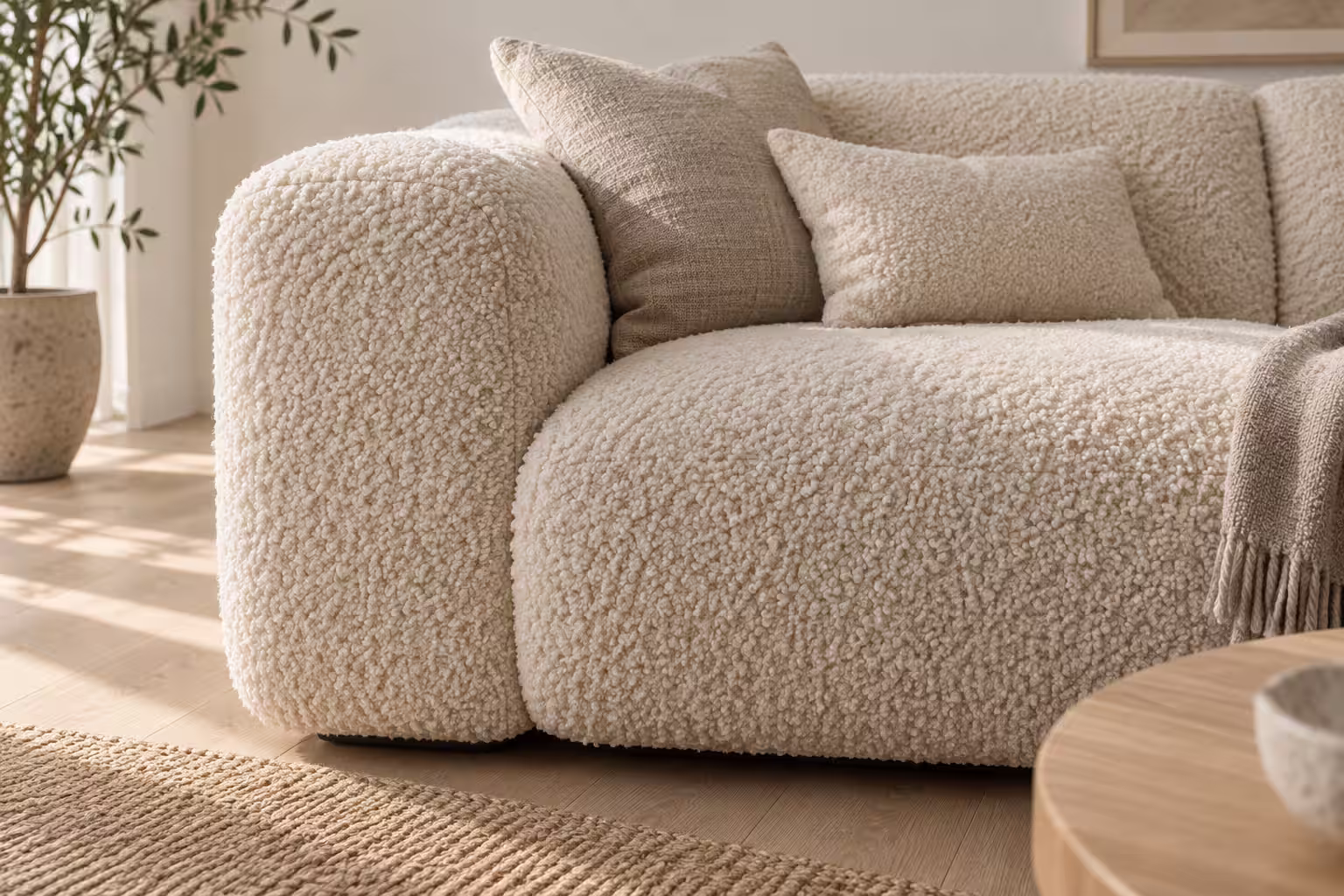 Närbild på en offwhite soffa i bouclé där de vävda öglorna syns tydligt i sidoljus